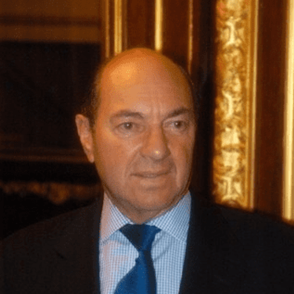 A white man wearing a suit, with a blue tie.