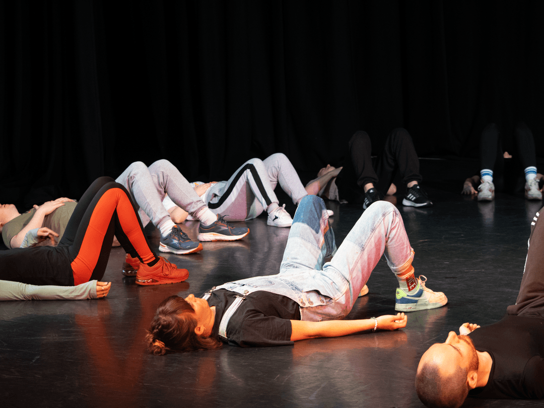 Members lying down with their knees up in a circle doing a warm up exercise together