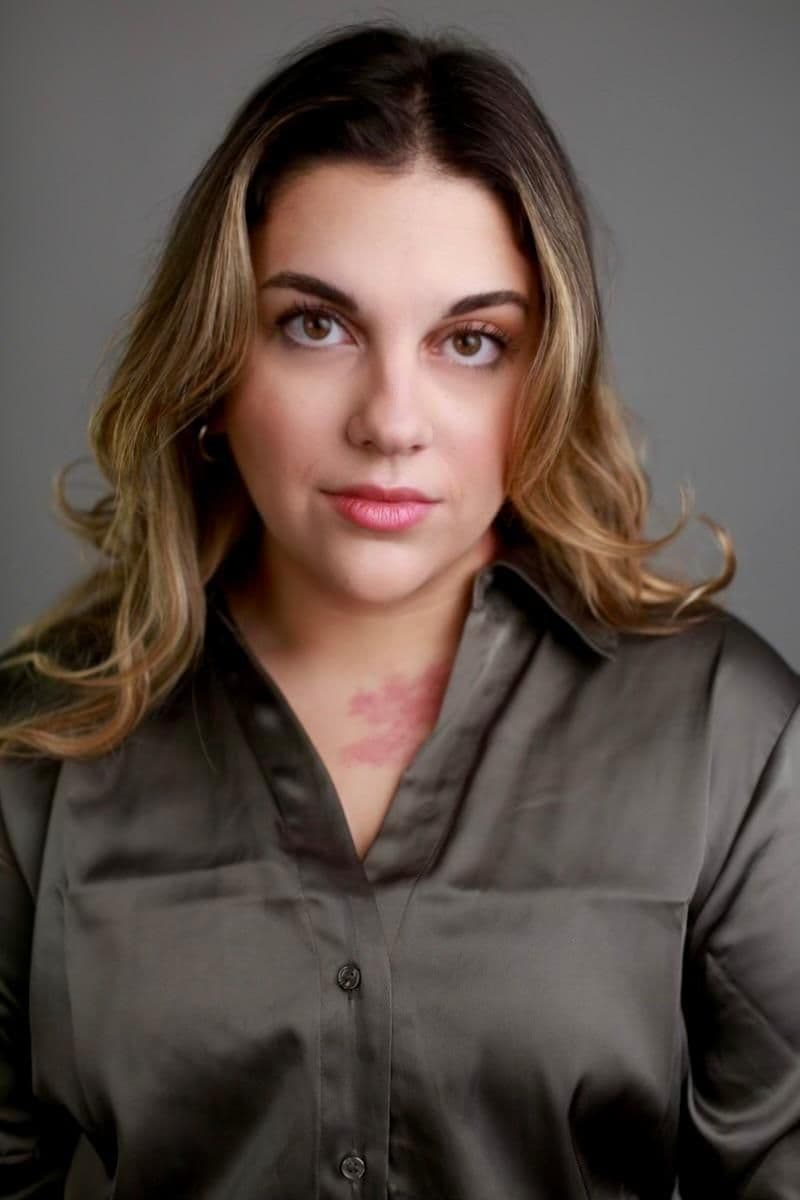Alara Koroglu headshot. A turkish woman with blonde and brown hair, wearing a grey satin shirt.