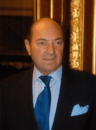 A white man wearing a suit, with a blue tie.