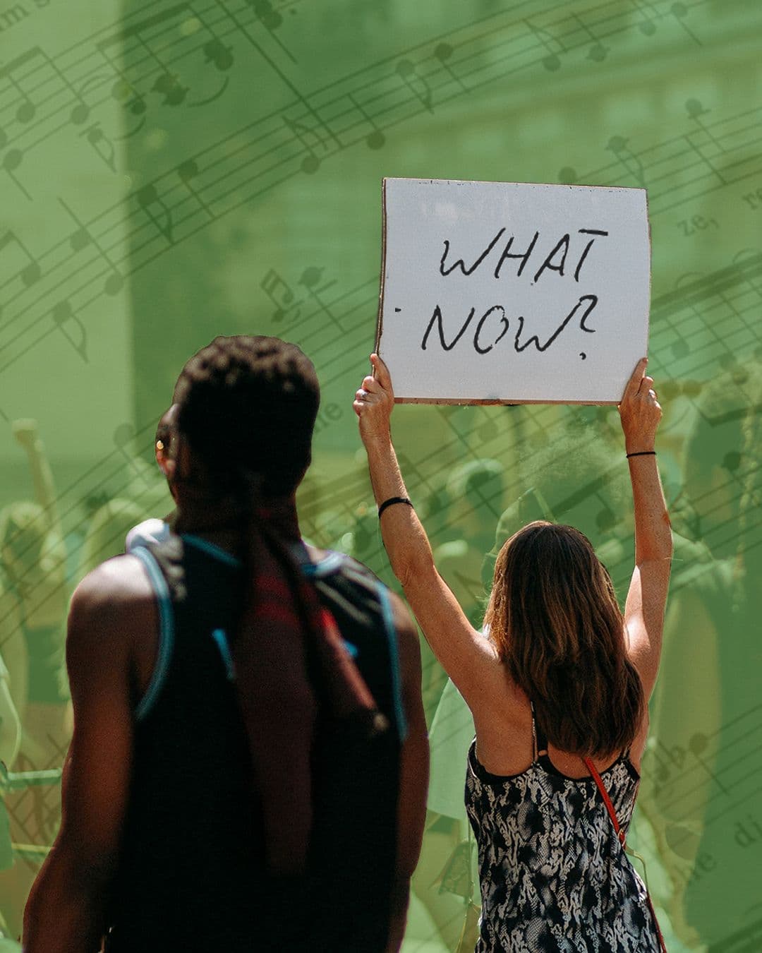 A person holds a sign reading "WHAT NOW?"