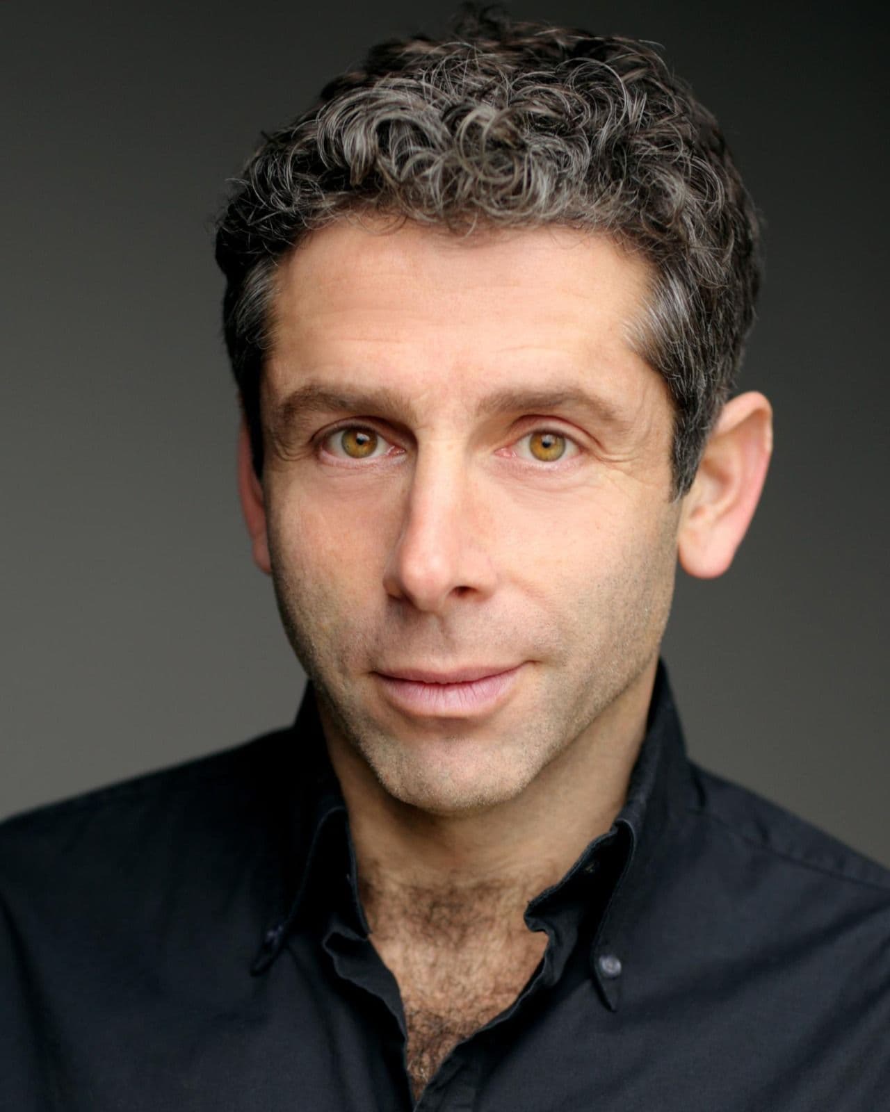 Elliot Levey headshot - black shirt, with dark background