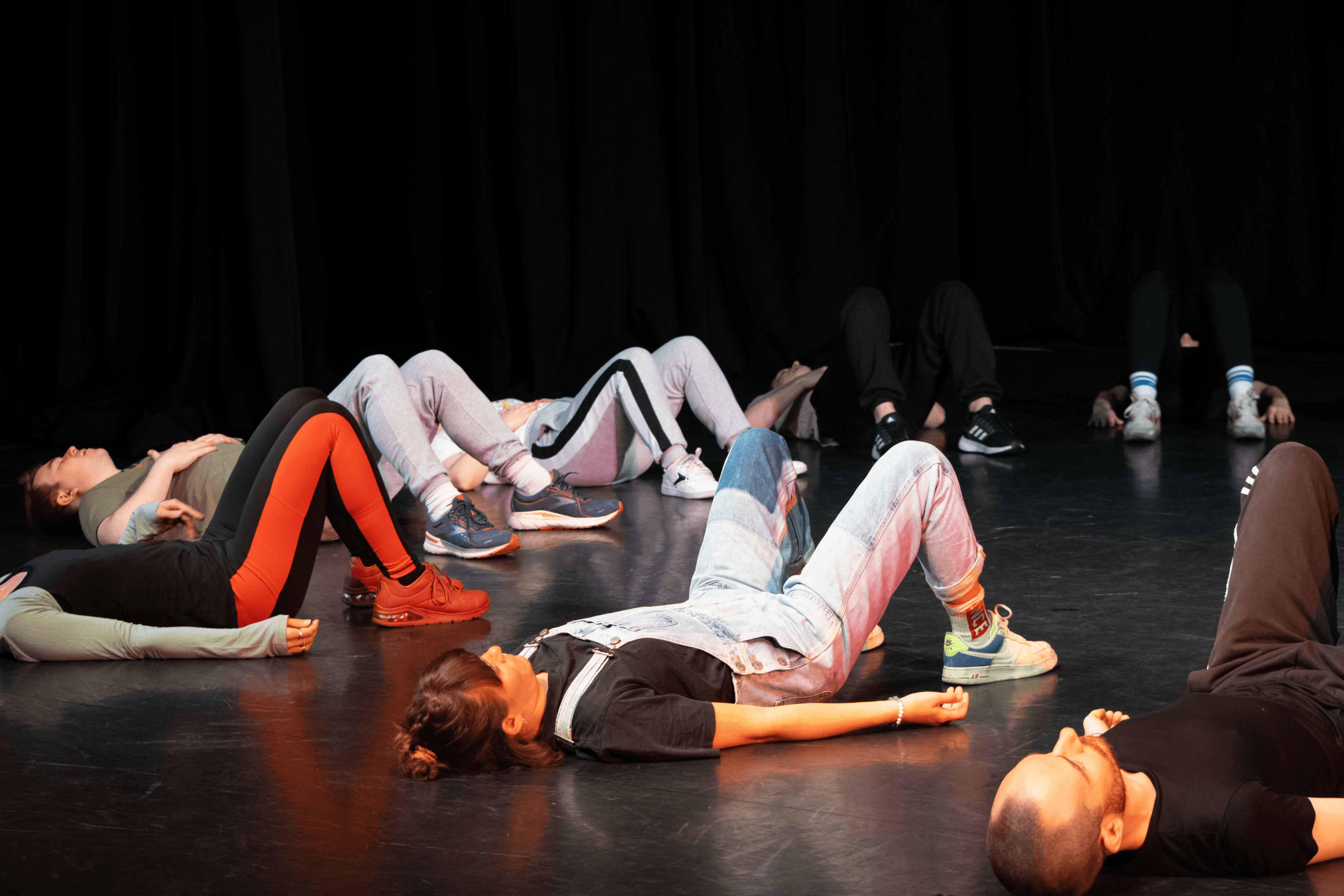Members lying down with their knees up in a circle doing a warm up exercise together