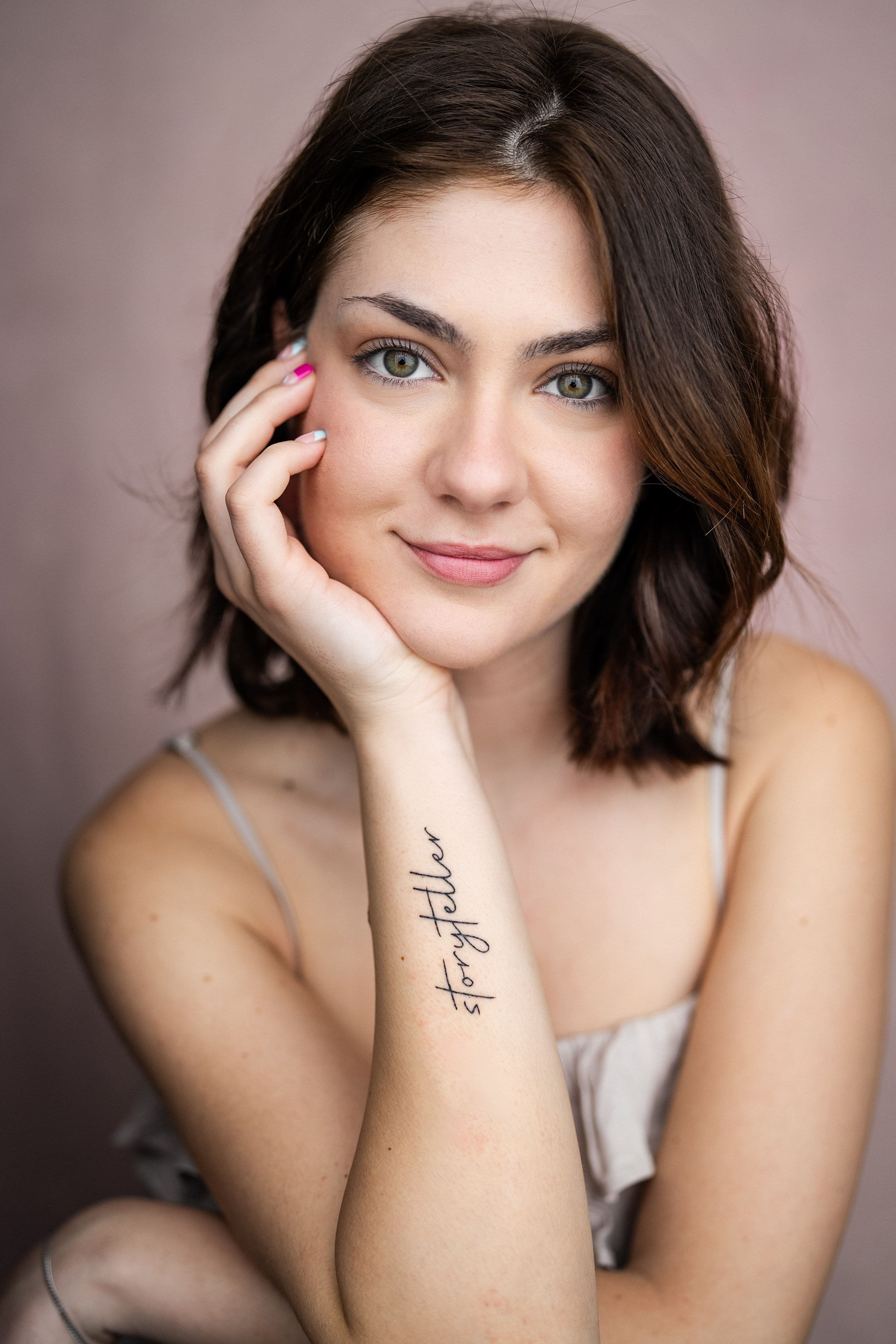 Gabriela Chanova Headshot. A Bulgarian white woman with brown eyes, with her hand up to her face. Short brown hair, a closed smile. 