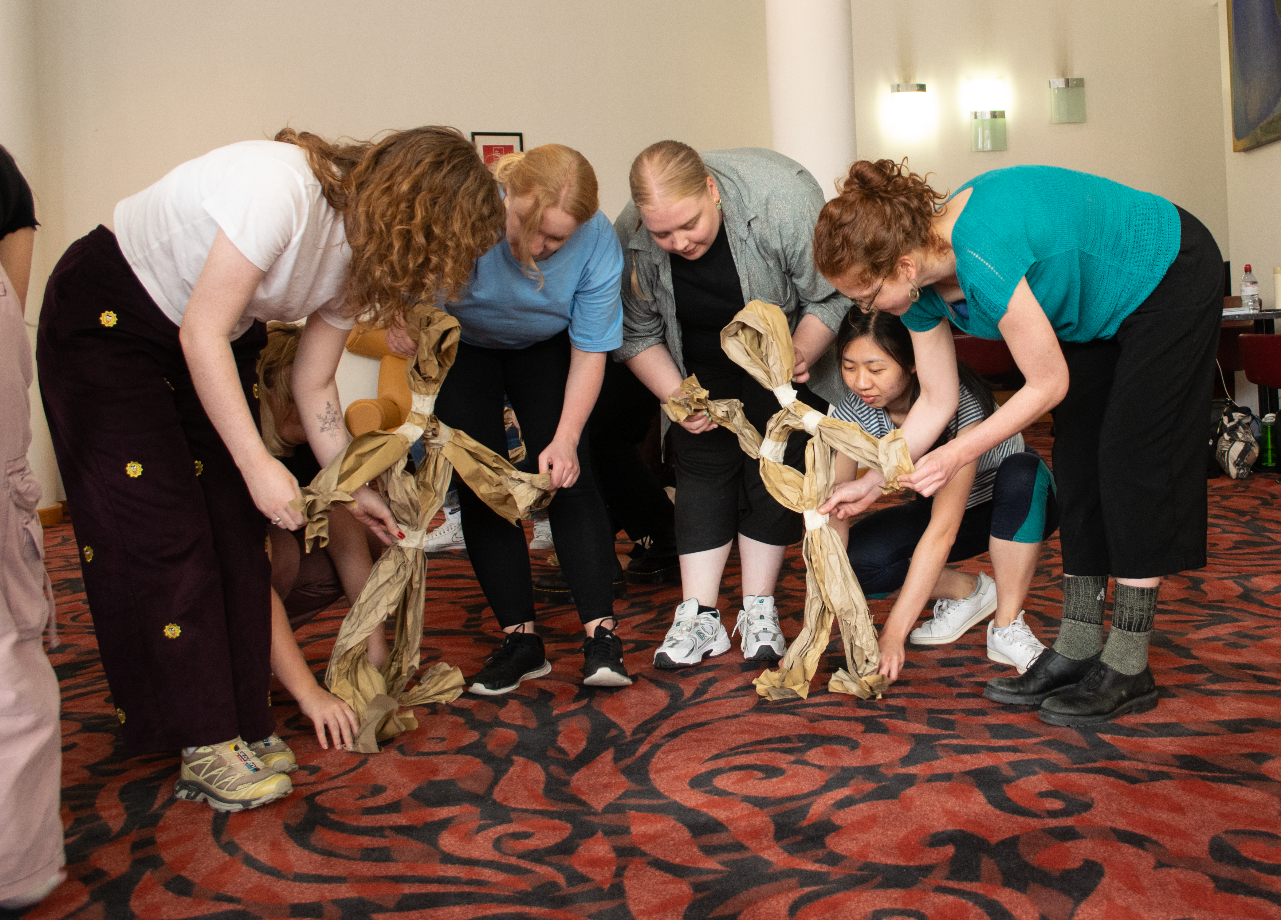 Members bending down to navigate their paper puppet.