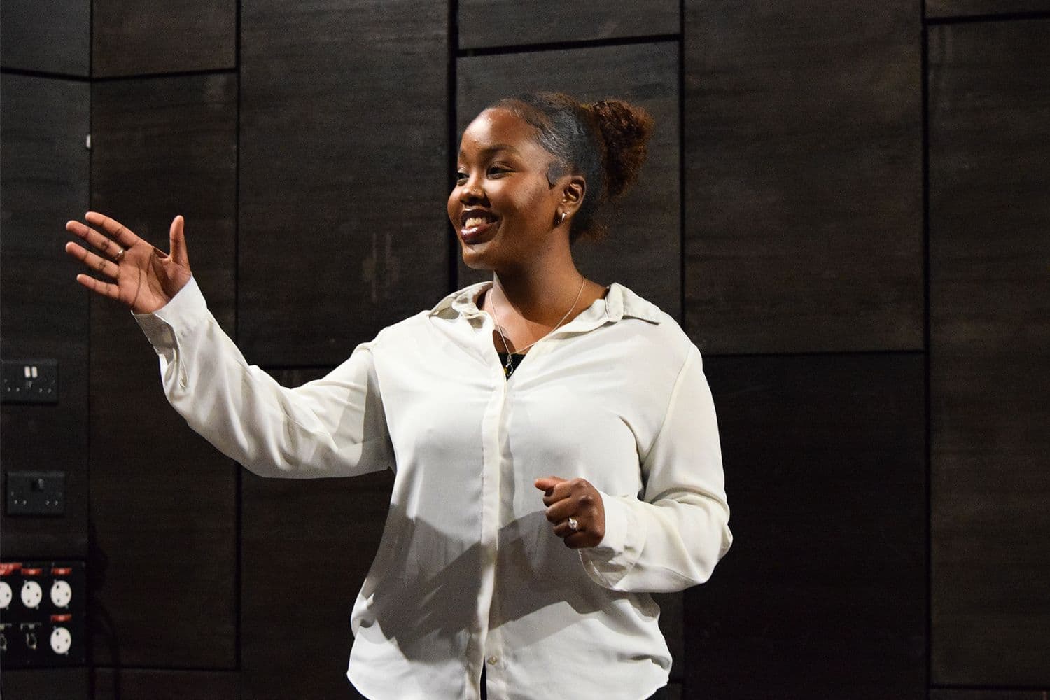 Savannah, a woman in a white blouse, gestures while acting as part of Script Scratch