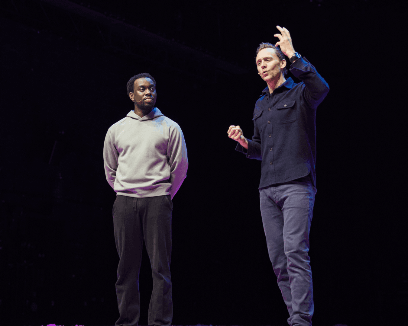 Tom Hiddleston stands on a stage with a Masterclass Member. 
