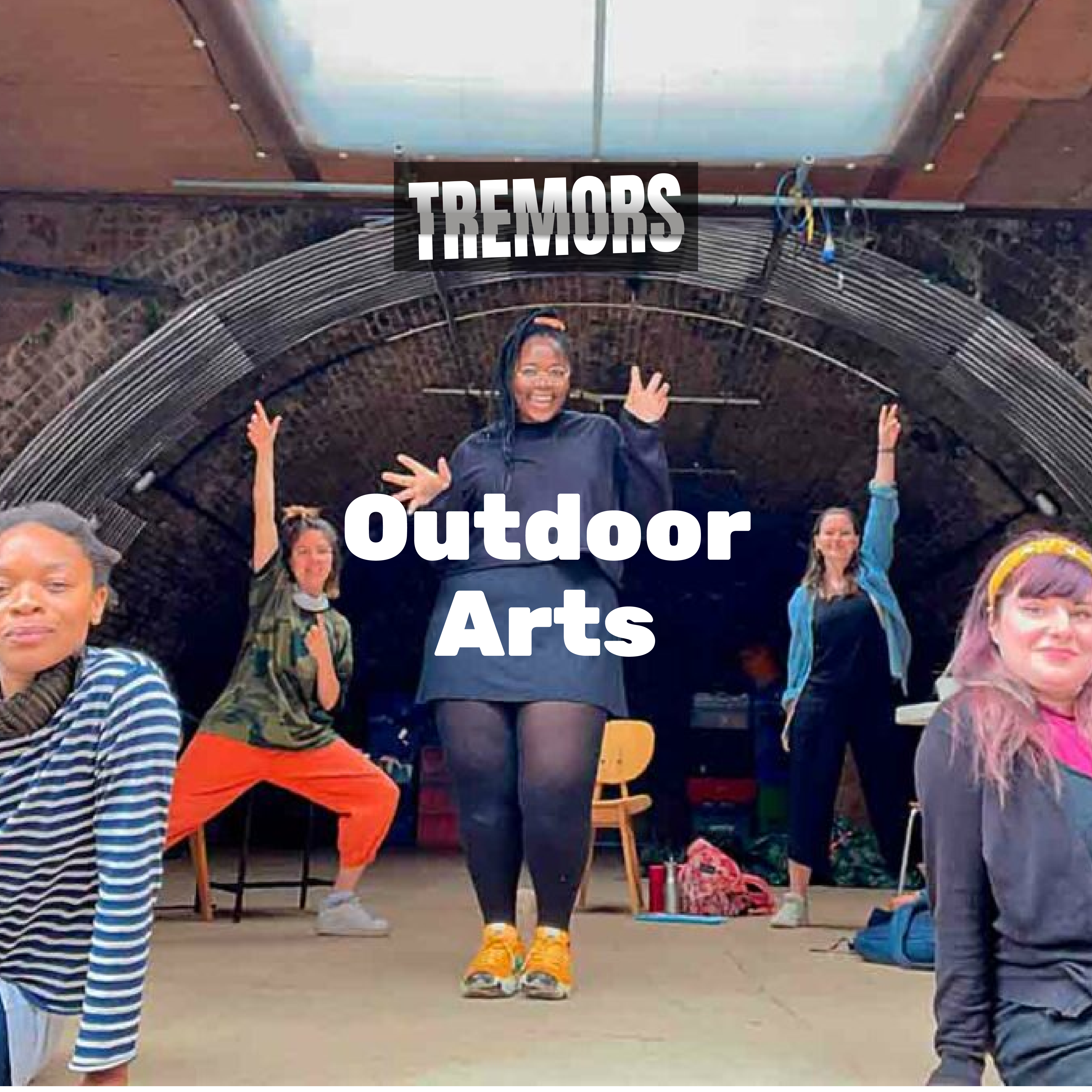 Image of Coney team in rehearsals on a stage, 5 people on stage. 2 with their arm raised and one with jazz hands. The final two sat at the front. All looking straight into the camera.