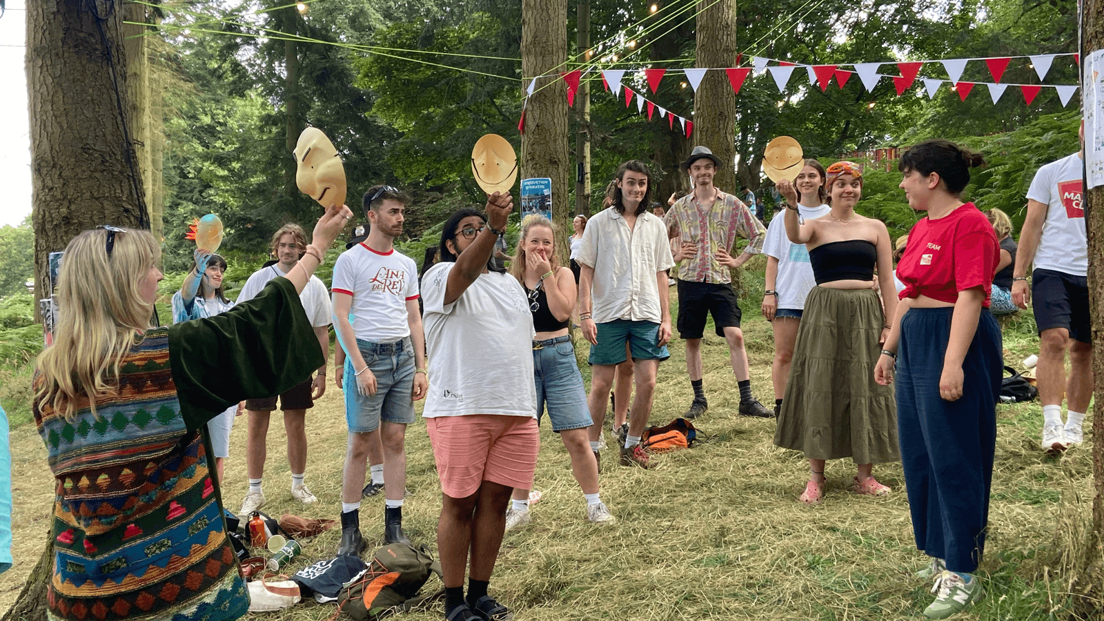 A group of young people doing a mask workshop with Masterclass member Georgie, at Latitude Festival out in the woods.