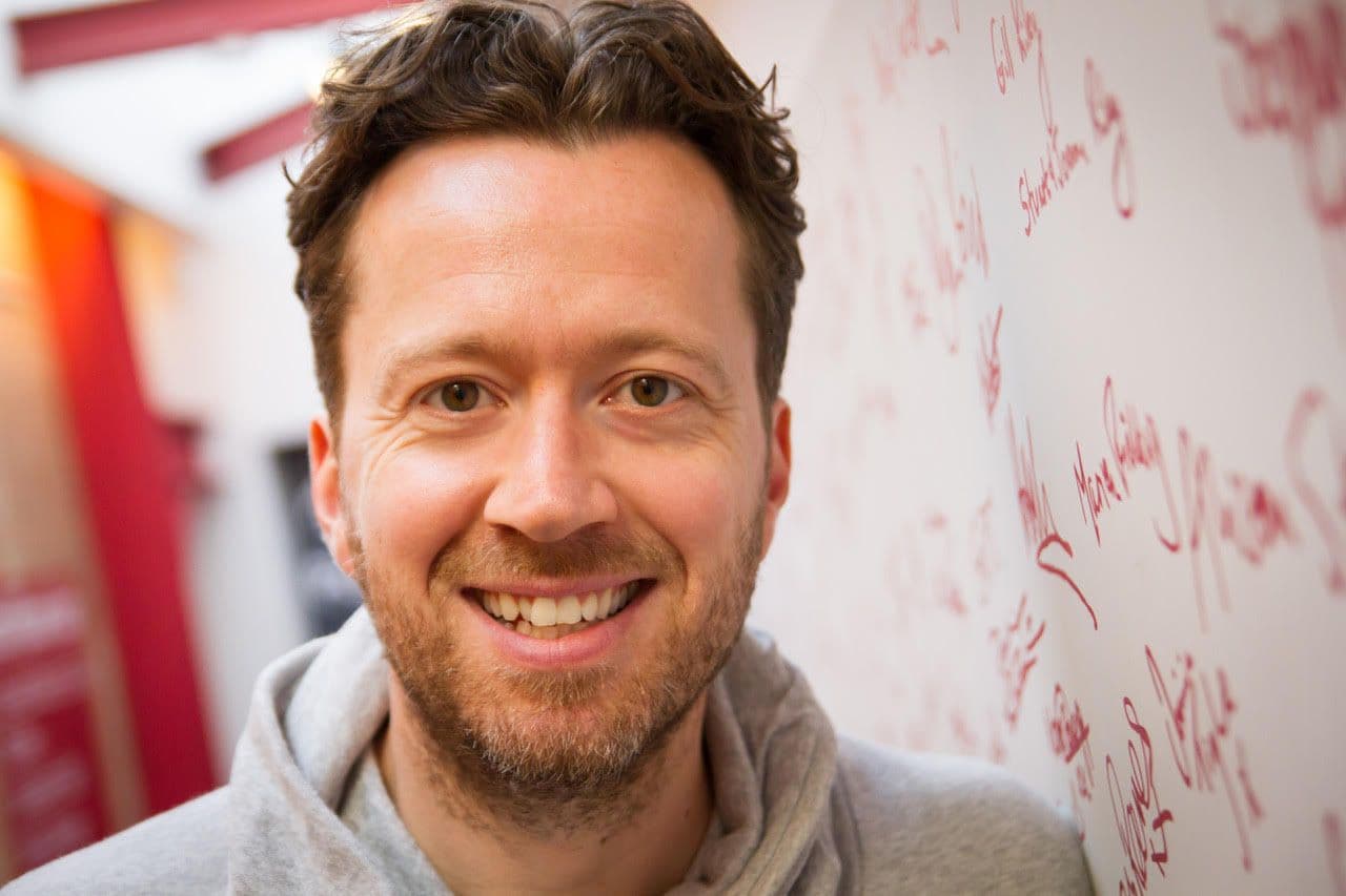 Jez Bond Headshot infront of signed wall at the Park Theatre