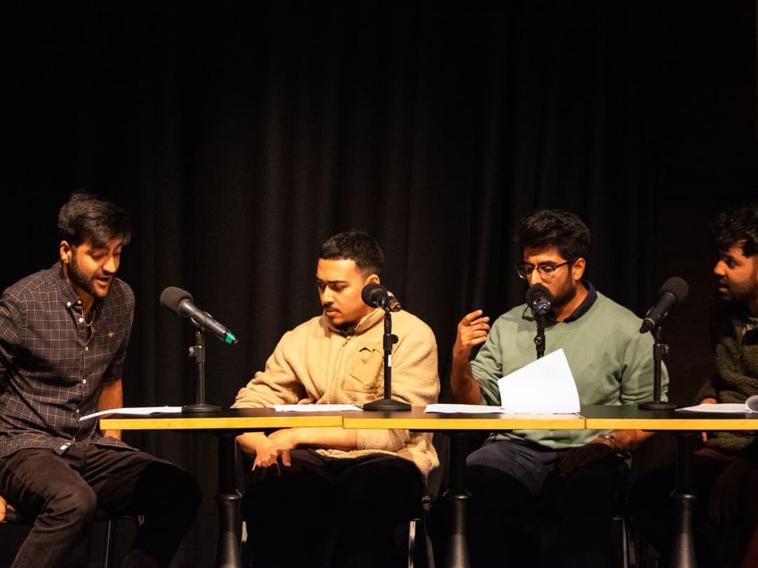 Four members seated at a table with microphones, reading The Waiting Room by Akshay Sharan