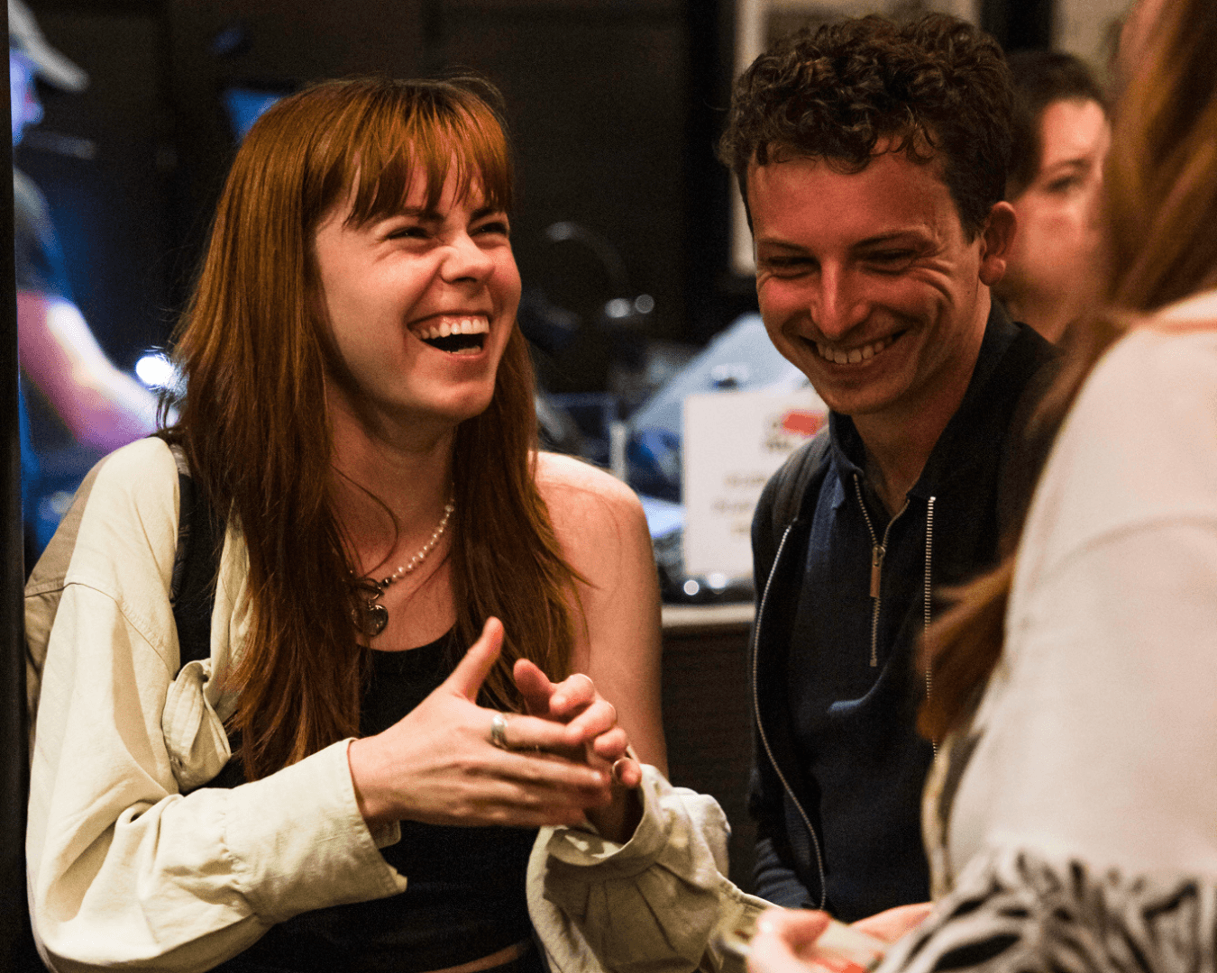 Group of young adults laughing and enjoying a conversation in an indoor casual setting.